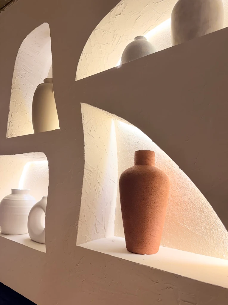 Pared con nichos arqueados y jarrones de cerámica terracota y crema, inspirados en la arquitectura griega